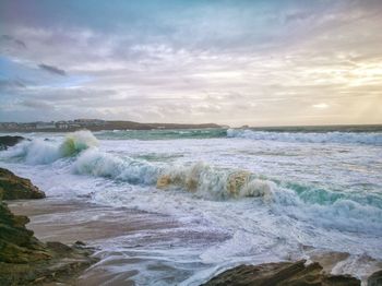 Waves rushing towards shore against sky