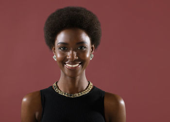 Portrait of young woman standing against yellow background