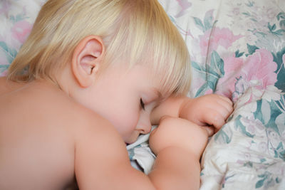Little boy sleeping on white pillow. beautiful baby child with long blonde hair. close-up face