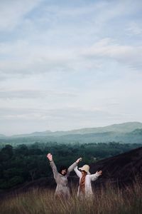 Panoramic view of people sitting on land against sky