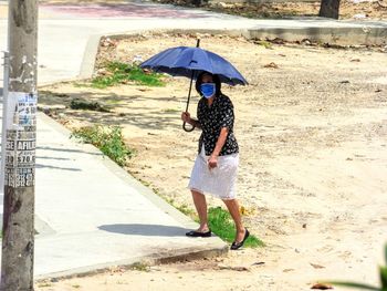 Woman with umbrella walking on street