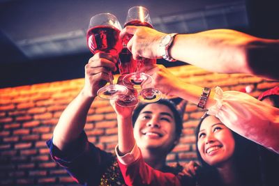 Low angle view of friends toasting drinks at christmas party