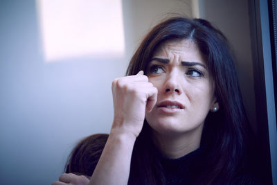 Close-up of worried woman looking away by window