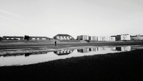 Mid distance view of mid adult man standing at riverbank against clear sky