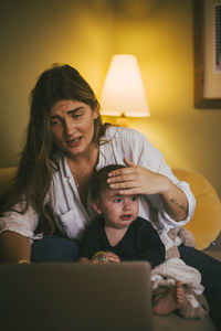 Mother with baby girl taking advice through video call on laptop at home