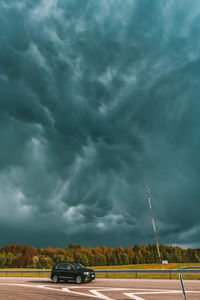 Car on road against storm clouds