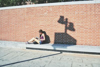 Woman sitting on brick wall