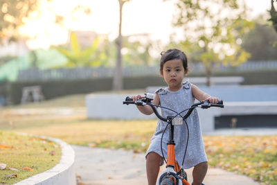 Cute little girl riding her orange bike in the park