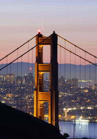 Illuminated bridge over river at night