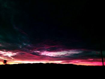 Silhouette landscape against dramatic sky at sunset