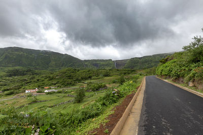 Road amidst green landscape against sky