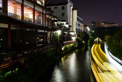 Canal amidst illuminated buildings in city at night