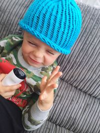 High angle view of child making face while sitting on sofa