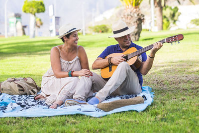 Happy woman listening to man playing guitar