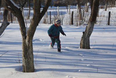 Full length of boy running on snowy field