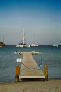 Sailboats on sea against clear sky