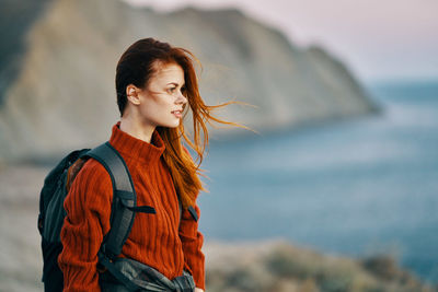 Young woman looking away while standing outdoors