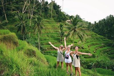 Friends standing on field against trees in forest