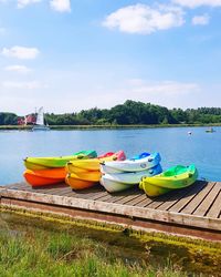 Kayaks on pier by lake against sky