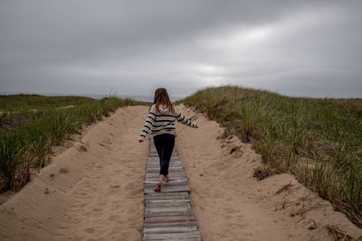 View from behind as girl walks down board walk to lake michigan