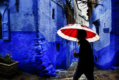 Woman standing on wet umbrella against building