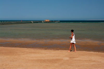 Rear view of man standing on beach against sky