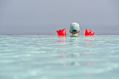 Rear view of man swimming in sea against sky
