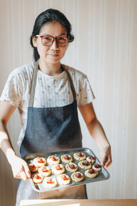 Portrait of woman showing food in tray at home