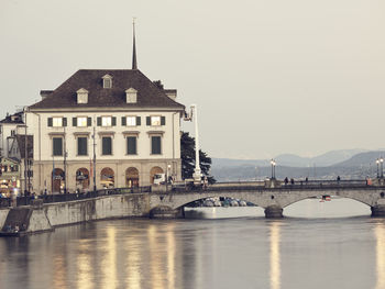 Arch bridge over river against buildings in city