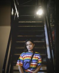 Portrait of young woman standing on staircase