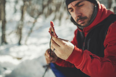 Portrait of man holding smart phone while standing outdoors