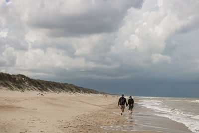 Couple walking on a huge beach in belgium along the north sea