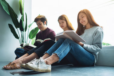 Friends using mobile phone while sitting on sofa at home