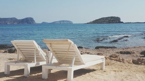 Chairs on beach against clear sky