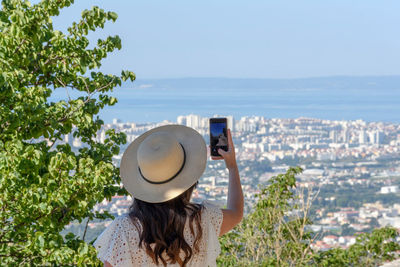 Young woman in white dress standing at klis fortress taking photos of city of split in croatia