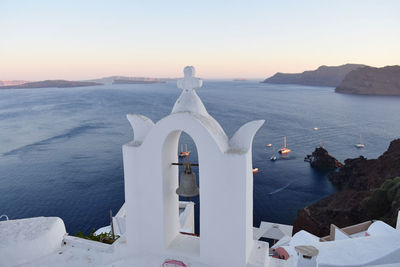 White building by sea against sky during sunset