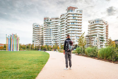 Full length rear view of man standing in city against sky