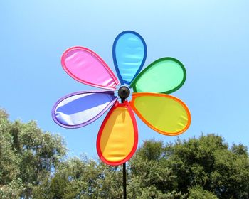 Flower wheel multi colored,  low view of  trees against blue sky