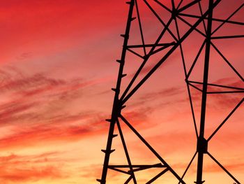 Low angle view of silhouette electricity pylon against dramatic sky