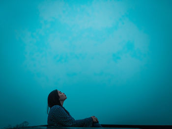 Woman standing against blue sky