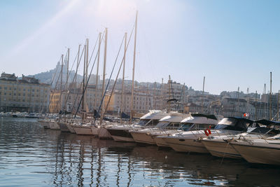 Sailboats moored at harbor against clear sky