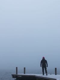 Rear view full length of man standing by sea on pier