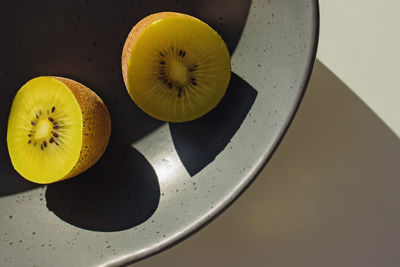 Two halves of kiwi fruit on the plate with natural sunlight shadows