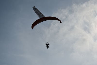 Low angle view of man paragliding against sky