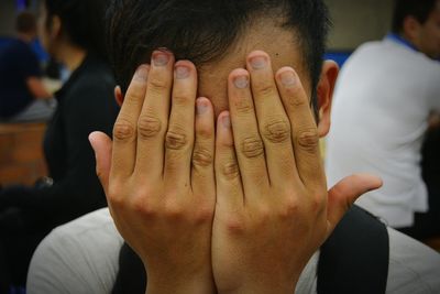 Close-up of teenage boy covering face