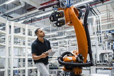 Technician examining industrial robot in a factory