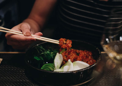 Close-up of person holding food in bowl on table