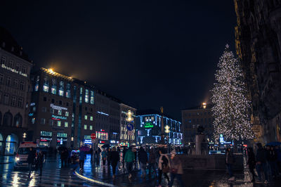 People on illuminated christmas tree at night