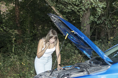 Woman standing near a parked broken down car having trouble with her vehicle. woman waiting for help