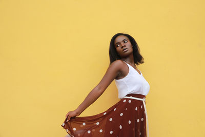 Profile photo of a fashion model, standing up, empty space isolated on a yellow color background